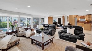 A spacious living area with leather sofas, a coffee table, and a view of a swimming pool. - Waterfront With Pool Spa Tiki Bar and 1 Mile to Beach (Fort Lauderdale)