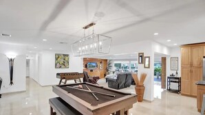 A pool table in a well-lit room with a ceiling fan, a billiards set, and a view of the outside. - Waterfront With Pool Spa Tiki Bar and 1 Mile to Beach (Fort Lauderdale)