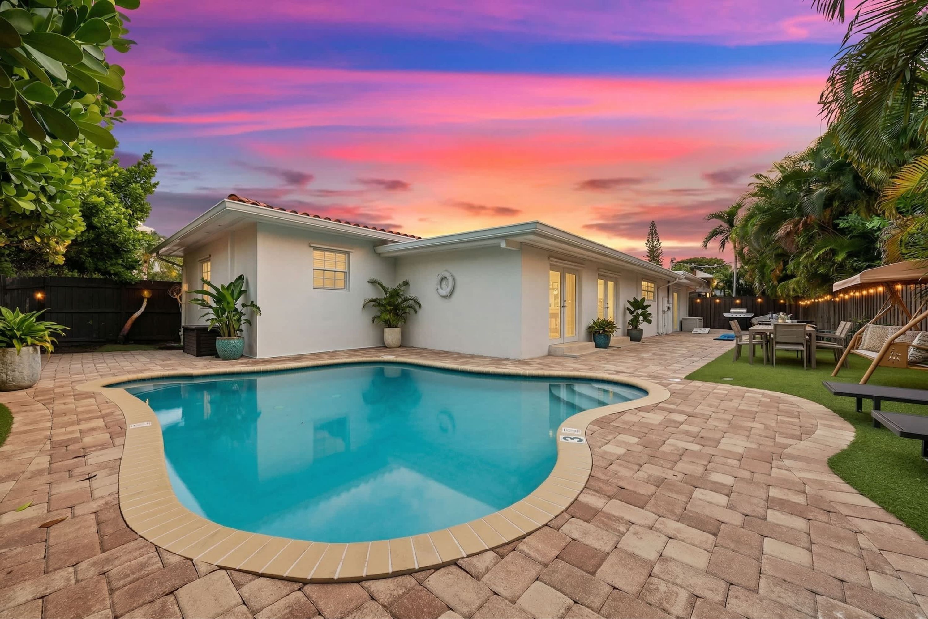Uma casa com piscina, um pátio e vista para o pôr do sol.