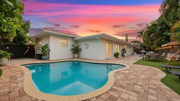 Uma casa com piscina, um pátio e vista para o pôr do sol.
