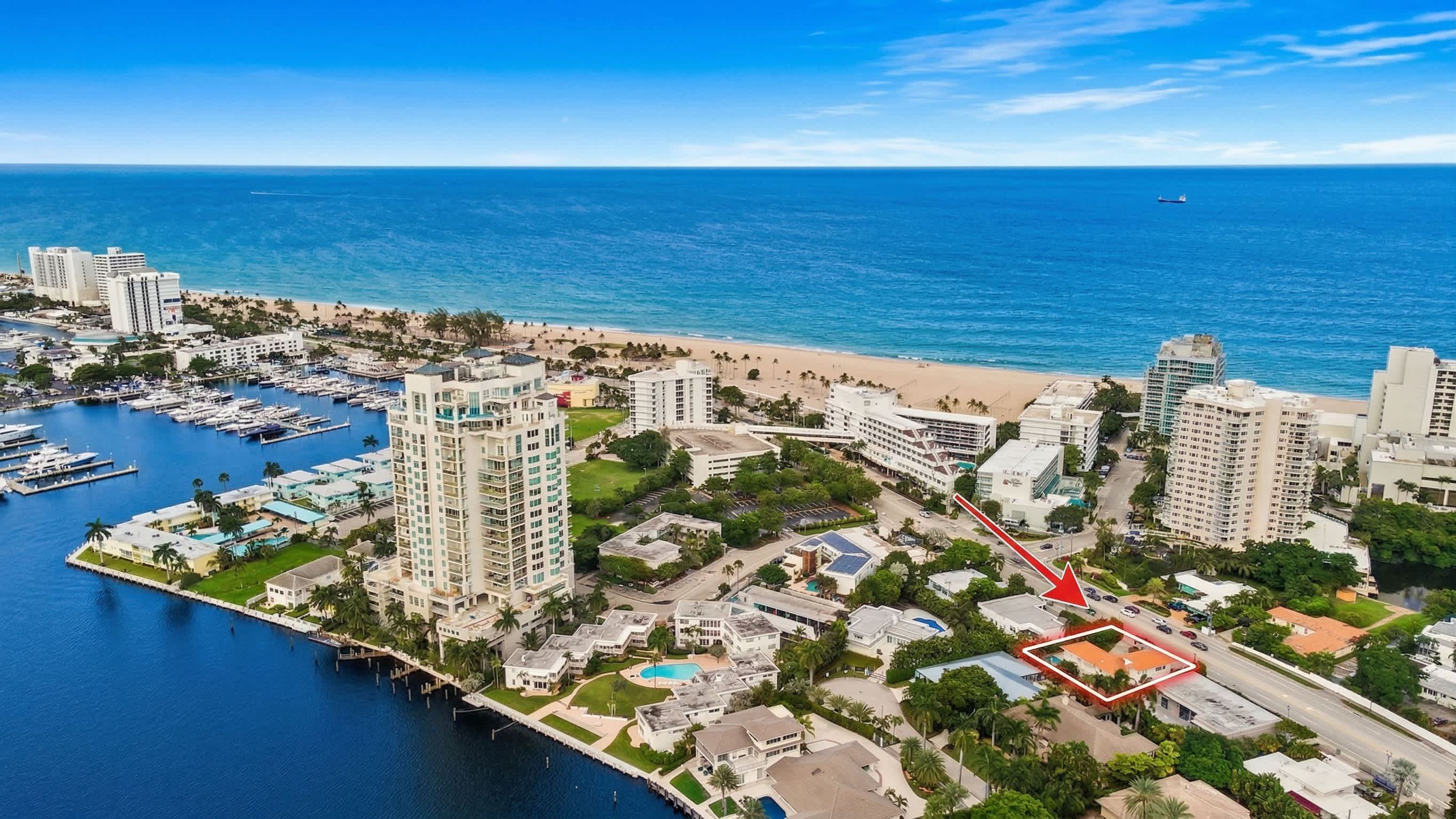 Vista aérea de uma área costeira com resort, marina, praia e edifícios altos.