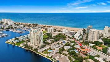 Vista aérea de uma área costeira com resort, marina, praia e edifícios altos.