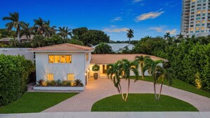 A modern two-story house with a tiled roof, surrounded by lush greenery and palm trees. - 6 BR Villa Steps to Ocean Pool Sauna Jacuzzi (Fort Lauderdale)