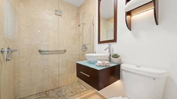 A modern bathroom with a glass-enclosed shower, a white sink, and a toilet.