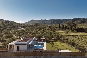 Ein modernes Haus mit Swimmingpool, umgeben von einem Weinberg und einer hügeligen Landschaft.