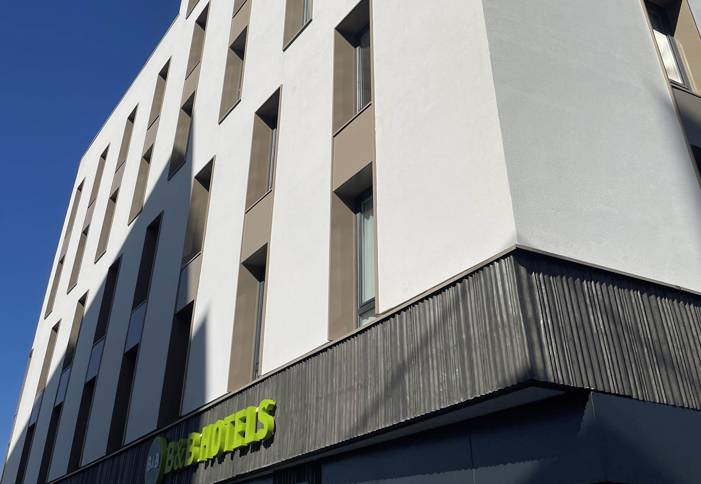 En hotellbyggnad med en modern fasad, stora fönster och en tydlig skylt med texten ”B&B HOTELS” på bottenvåningen.
