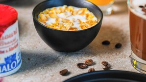 A bowl of cereal with milk, a glass of orange juice, and a container of milk. - B&B Hotel Magnanville (Magnanville)