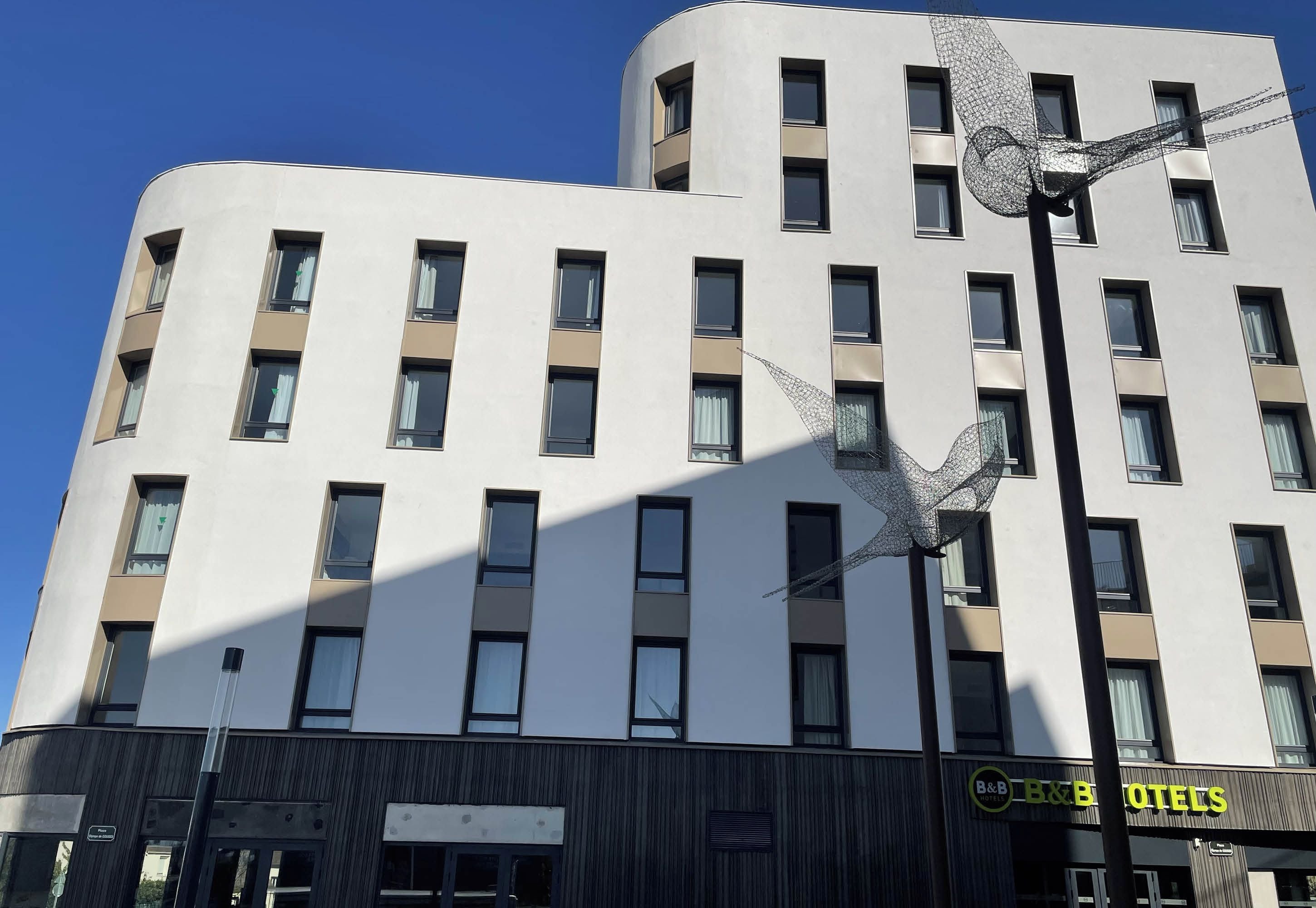 Un hôtel à plusieurs étages, doté d’une façade moderne, avec une série de fenêtres et de balcons.