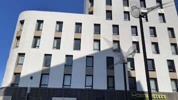 Un hôtel à plusieurs étages, doté d’une façade moderne, avec une série de fenêtres et de balcons.