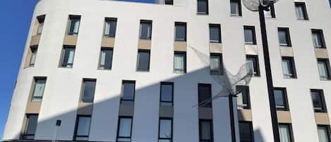 A multi-story hotel with a modern facade, featuring a series of windows and balconies.