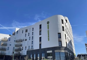 A modern hotel with a white facade, multiple balconies, and a prominent B&B logo.