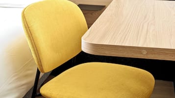 Una silla tapizada de color amarillo y una mesa de madera en una habitación con cama.