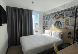Una habitación de hotel con una cama grande, una ventana con cortinas y un mural en la pared.