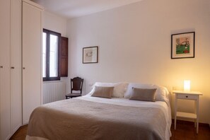A bedroom with a bed, a chair, a bedside table with a lamp, and two framed pictures on the wall. - The Locksmith's house by Maison Florence (firenze)