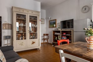 A dining area with a wooden table, chairs, a cabinet with glass doors, a television, and a refrigerator. - The Locksmith's house by Maison Florence (firenze)
