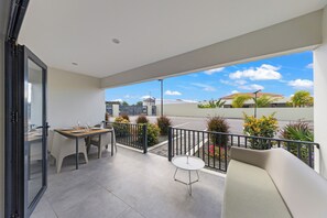 Ein Balkon mit Esstisch und Stühlen, einem kleinen runden Tisch und einer Couch.