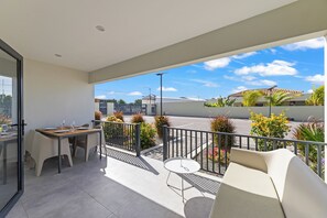 Ein Balkon mit Tisch und Stühlen, einem kleinen runden Tisch und einer Couch.