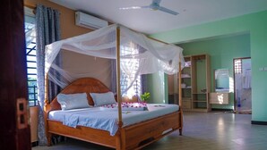 Quarto com cama de madeira, ventoinha no teto, guarda-roupa e janela com cortinas.