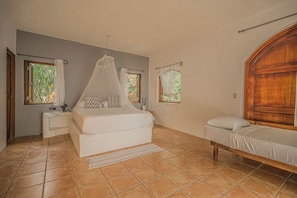 A bedroom with a bed, bedside tables, a nightstand, a window with a view, and a wooden headboard.