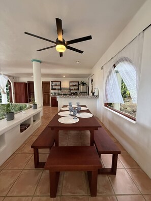 A spacious dining area with a long wooden table, multiple chairs, and a ceiling fan.