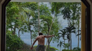 Un homme fait du skateboard dans un espace extérieur tropical, avec une piscine et des palmiers.
