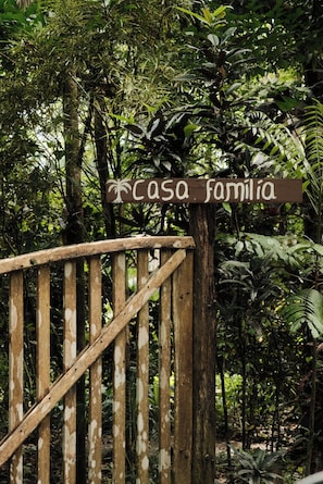 A wooden gate with a sign that reads 'casa familiaria' in a lush, green environment.