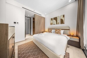 Ein modernes Hotelzimmer mit einem großen Bett, einem Nachttisch mit Lampe, einem Kleiderschrank und einem Wandbild.