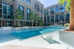 Ein modernes Gebäude mit Pool, Palmen und dem Schriftzug 'THE ALCOGRAP' an der Fassade.