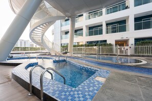 Ein modernes Gebäude mit Poolbereich, einschließlich einer Wendeltreppe und einem rechteckigen Pool mit Fliesenboden.