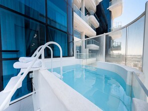 Ein moderner, überdachter Pool mit Glasgeländern und freiem Blick auf die Stadt, mit weißer Fassade.