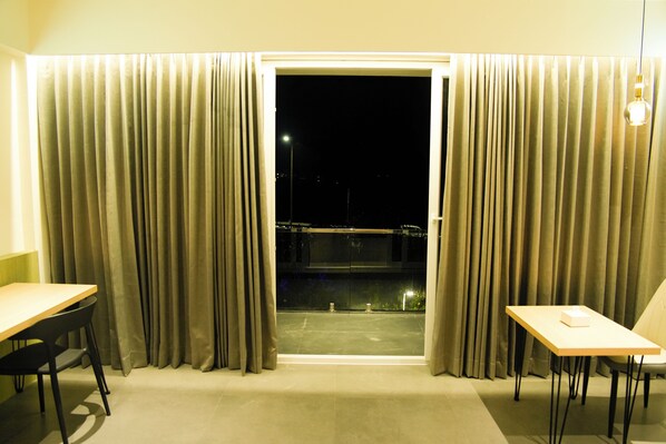 Una habitación con puerta corredera que da a un balcón, una mesa y una silla.