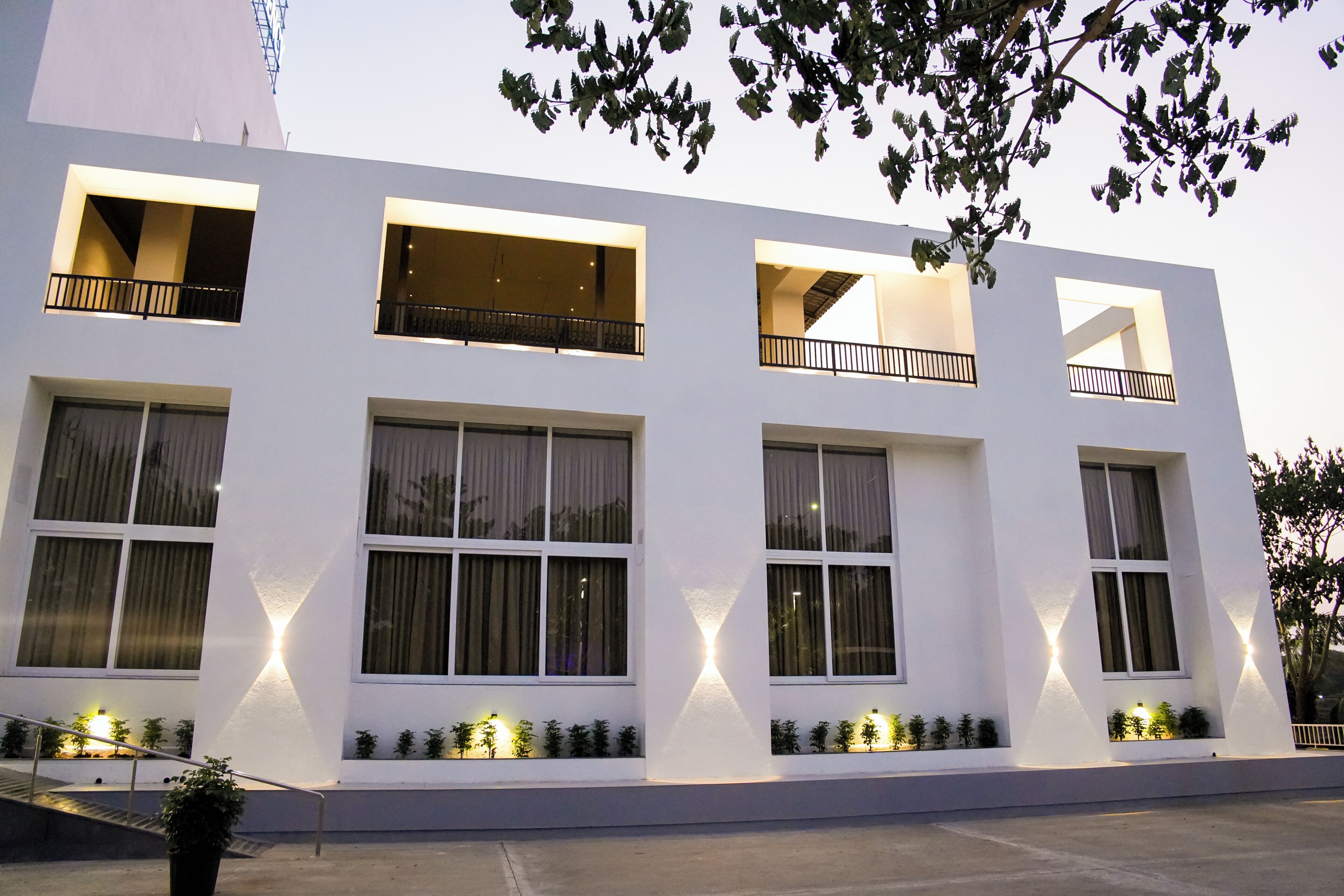 A modern building with multiple windows and balconies, a staircase, and small plants along the windows.