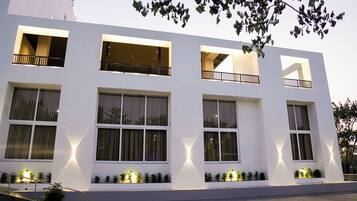 A modern building with multiple windows and balconies, a staircase, and small plants along the windows.