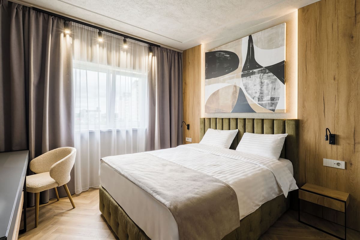A modern hotel room with a large bed, a desk, and a chair.
