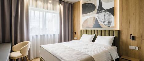 Una habitación de hotel moderna con una cama grande, un escritorio y una silla.