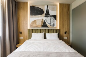 Ein modernes Hotelzimmer mit einem großen Bett, einem Holzkopfteil und abstrakter Kunst an der Wand.