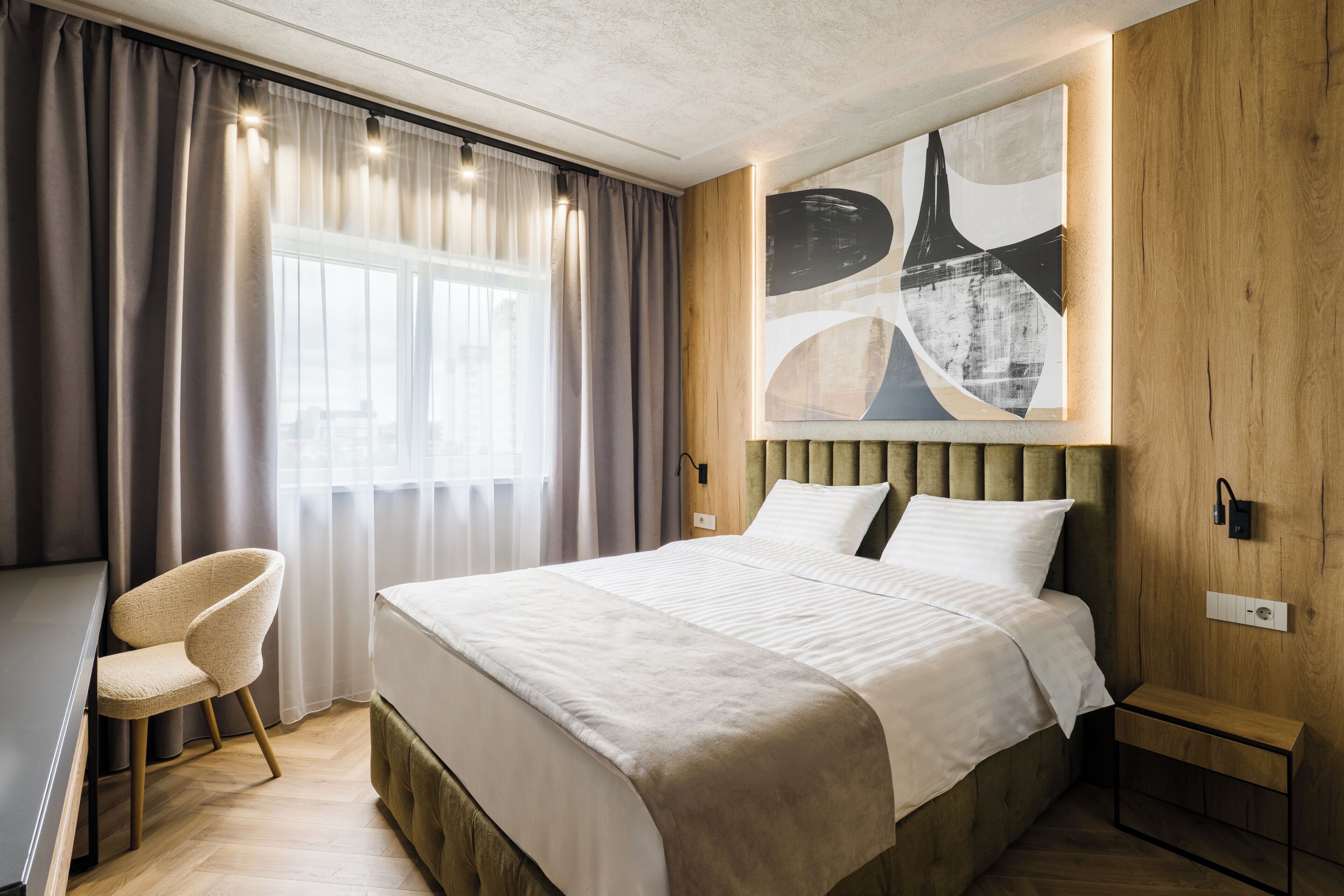 Ein modernes Hotelzimmer mit einem großen Bett, einem Schreibtisch und einem Stuhl.