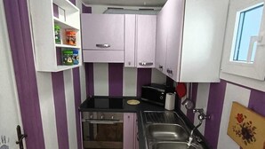 Una cucina compatta con forno a incasso, lavello e finestra.