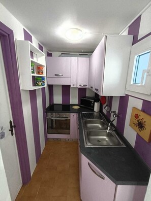 A compact kitchen with a built-in oven, a sink, and a window. - Just a stone's throw from the sea—whether it's a sandy beach, rocky shore, or pebble beach—Casa Magia (Marina di Pisa-tirrenia-calambr)