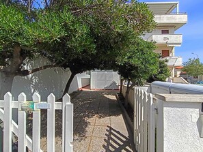 A narrow street with a white picket fence, a tree, and a building with a white facade and balconies. - Just a stone's throw from the sea—whether it's a sandy beach, rocky shore, or pebble beach—Casa Magia (Marina di Pisa-tirrenia-calambr)
