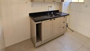 Een keuken met een zwart aanrecht, roestvrijstalen kastjes en een spoelbak.