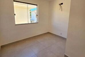 Ein Zimmer mit großem Fenster, gefliestem Boden und einer fest installierten Steckdose.