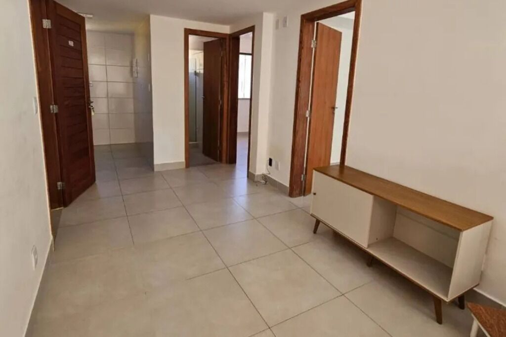 A hallway with tiled flooring, wooden doors, and a white console table.