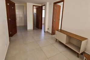 Um corredor com piso ladrilhado, portas de madeira e um aparador branco.