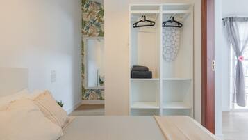 Ein Schlafzimmer mit einem Bett, einem Kleiderschrank und einem durchgegangenen Tür erkennbaren Badezimmer.