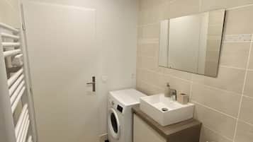Een moderne badkamer met een wasmachine, wastafel en toilet.