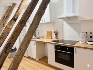 A modern kitchen with white cabinets, a wooden countertop, a built-in oven, and a coffee maker. - Caporizon—Les Balancoires—2 bedrooms—Right in the center (Sarlat-la-Canéda)