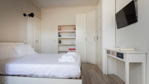 Ett hotellrum med en säng, ett skrivbord, en tv och en garderob.