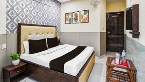 Una habitación de hotel con cama, mesita de noche, una obra de arte en la pared y una mesita con bandeja.