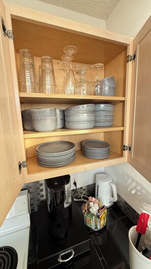 Eine Küche mit Holzschränken, einer Kaffeemaschine, einem Wasserkocher und diversen Küchenutensilien.